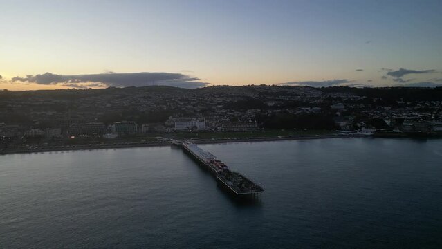 Paignton, Torbay, South Devon, England: DRONE VIEWS: Paignton Pier at sunset. Paignton is a popular UK holiday resort; the Pier was completed in 1879 during the reign of Queen Victoria (Clip 4).