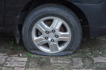 flat car tire in the parking lot, textured with bricks. seems to have been abandoned