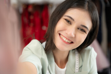 Beautiful woman holding camera and smile at her shop. She using camera to selfie at her studio.