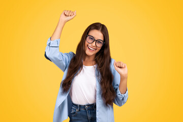 Glad shocked european teen woman in glasses exuberant celebrates win, rise fists