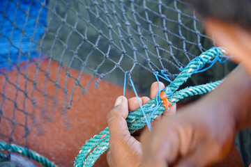 Close up View of Fisherman Fixing Fishing Net, knitting a trawl net, traditional way