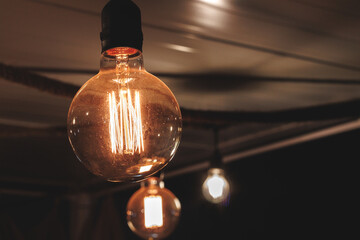 From below several light bulbs hanging under the ceiling in a dark room
