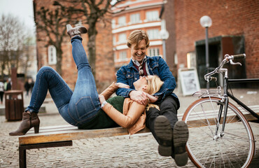 Middle aged Caucasian couple relaxing on the bench after riding a bicycle together in the city