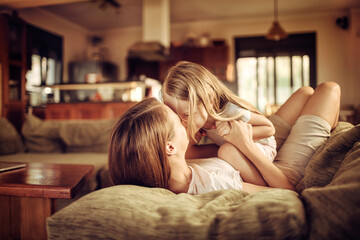 Young mother embracing her daughter on the couch at home