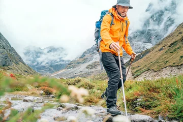 Cercles muraux Makalu Man with backpack and trekking poles crossing mountain creek during Makalu Barun National Park trek in Nepal. Mountain hiking and active people concept image.