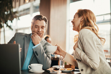 Young business coworkers enjoying a cup of coffee and discussing work in a café decorated for Christmas and the new year holidays