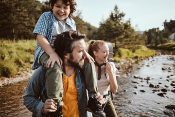 Happy young Caucasian family hiking through the forest in the mountains