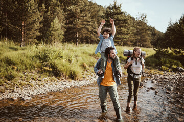 Happy young Caucasian family hiking through the forest in the mountains