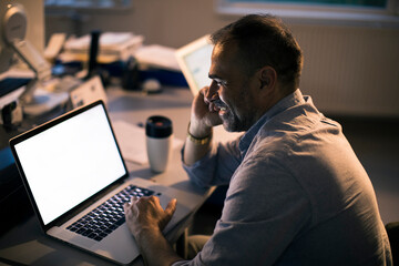 Middle aged architect using the laptop with a blank screen in his office