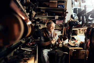Senior male shoemaker restoring a shoe in his old workshop in the city