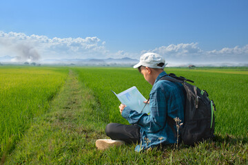 Young asian boy with backpack, map and binoculars in rice field, new edited.