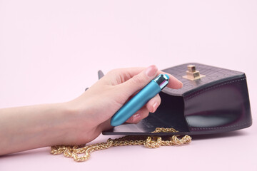 A blue bullet-dildo in a small black purse on a light background with copyspace text for a sex shop.