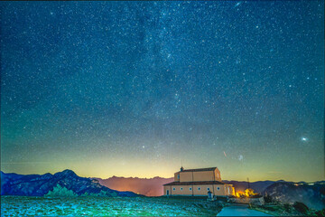 Un beau ciel étoilé avec la queue de la voie lactée au dessus de l'église de la Madone d'Utelle dans les Alpes du Sud - obrazy, fototapety, plakaty