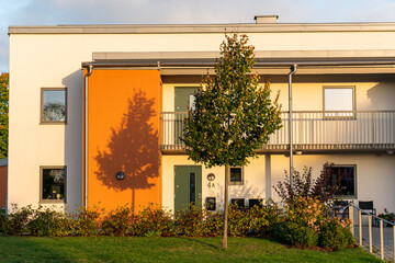 Beautiful shadow of a tree on a building during sunrise or sunset, silhouette. Autumnal tree, warm sunlight, cozy atmosphere outdoors. Modern and stylish residential building in Europe, Sweden.
