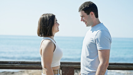 Beautiful couple smiling confident standing together looking each other at seaside