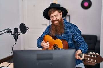 Young redhead man musician singing song playing classical guitar at music studio
