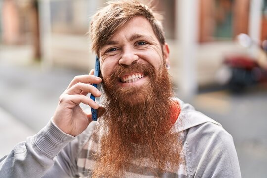 Young redhead man smiling confident talking on the smartphone at street