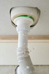 Water leaks at home in the bathroom. Water flows from the pipe under the sink