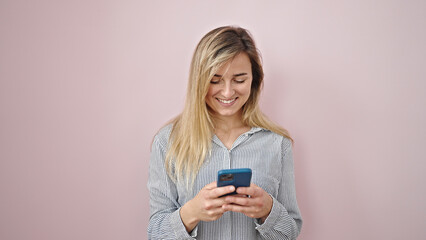 Young blonde woman smiling confident using smartphone over isolated pink background