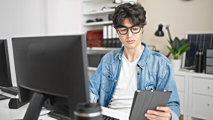 Young hispanic man business worker using touchpad and computer at office