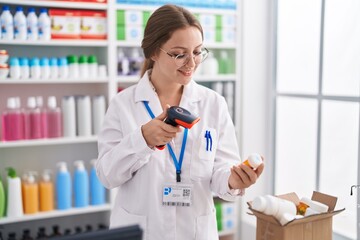 Young blonde woman pharmacist scanning pills bottle at pharmacy