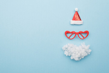 Santa hat, beard and glasses on color background top view