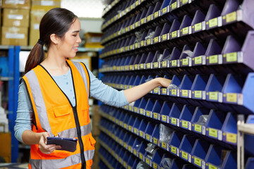 worker working on tablet and pick up spare parts from storage cabinet in the factory