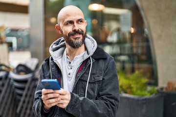 Young bald man smiling confident using smartphone at street