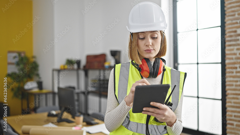 Wall mural Young blonde woman architect drawing on touchpad with serious expression at office