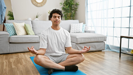 Young latin man sitting on floor training yoga at home