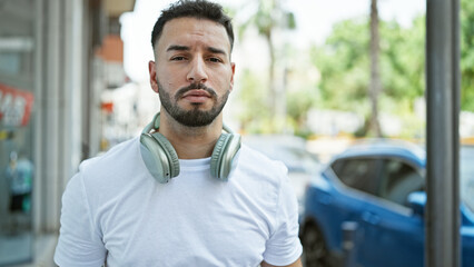 Young arab man wearing headphones at street