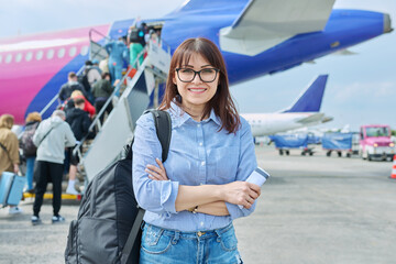 Middle aged woman with backpack, passengers boarding plane background