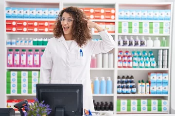 Zelfklevend Fotobehang Hispanic woman with curly hair working at pharmacy drugstore smiling pointing to head with one finger, great idea or thought, good memory © Krakenimages.com