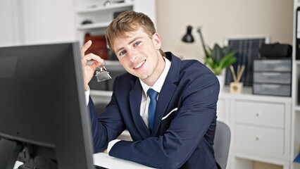 Naklejka premium Young caucasian man real state agent holding keys of new home at office