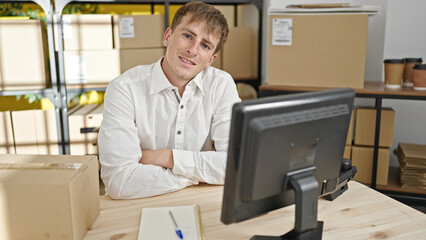 Young caucasian man ecommerce business worker smiling confident sitting with arms crossed gesture at office