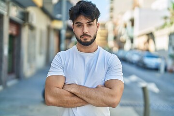 Fototapeta premium Young hispanic man standing with arms crossed gesture at street