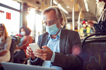 Senior businessman using his smartphone while commuting to work on a bus