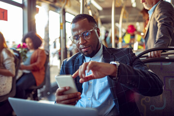 Young businessman using his smartphone while commuting to work on a bus