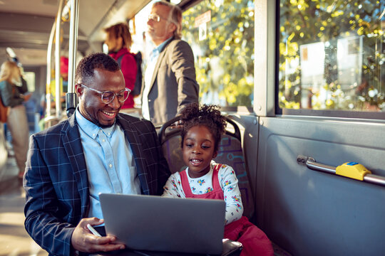 Young businessman using the laptop with his daughter on the bus