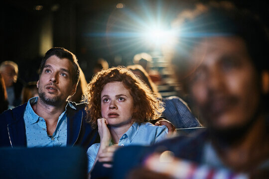 Young scared couple watching a horror film in the cinema