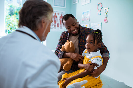 Young father comforting his daughter after a vaccination by the pediatrician in the clinic