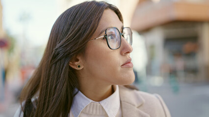 Young beautiful hispanic woman looking to the side with serious expression at street