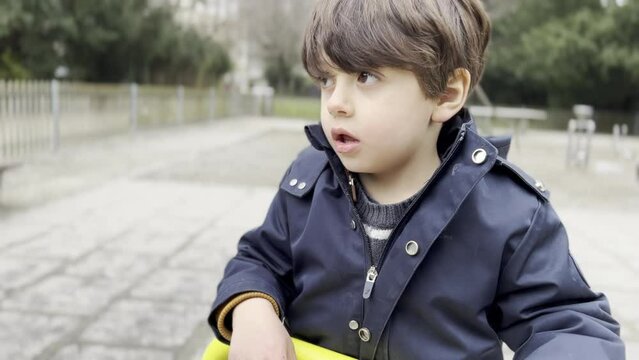 Absorbed Boy on Playground Carousel in Autumn, Daytime Fun Within Routine