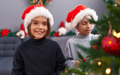 Adorable boys smiling confident decorating christmas tree at home