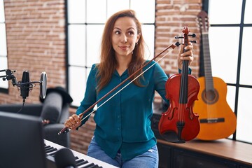 Brunette woman playing violin smiling looking to the side and staring away thinking. - obrazy, fototapety, plakaty