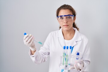 Young caucasian scientist woman working with laboratory samples relaxed with serious expression on...