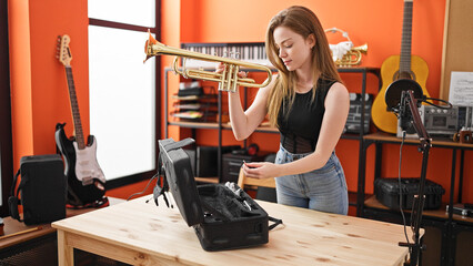 Young blonde woman musician cleaning trumpet at music studio