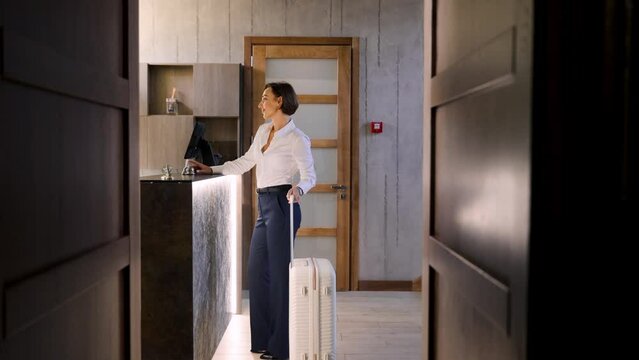 Business woman walking with luggage at the hotel into reception hall