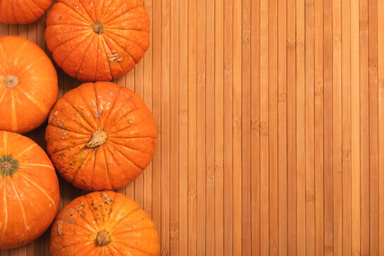 autumn orange halloween pumpkins on bamboo planks background. Сoncept Halloween celebration background, fall harvest, minimalism holiday decoration template. Top view, flat lay, copy space