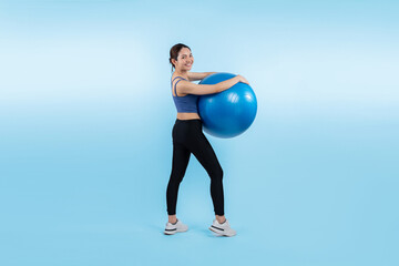 Fototapeta na wymiar Young attractive asian woman portrait in sportswear with fit ball targeting on abs muscle for effective energetic daily workout routine. Studio shot and isolated background. Vigorous